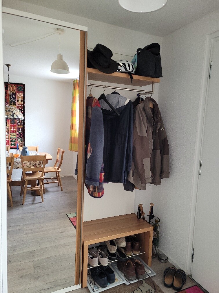 Eingangsbereich mit Garderobe, Jacken, Schuhregal und Schuhen.