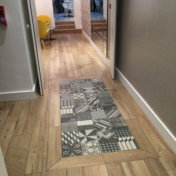 Flur mit Patchwork-Läufer auf Holzboden; Blick auf Sitzbereich mit gelben Sesseln.