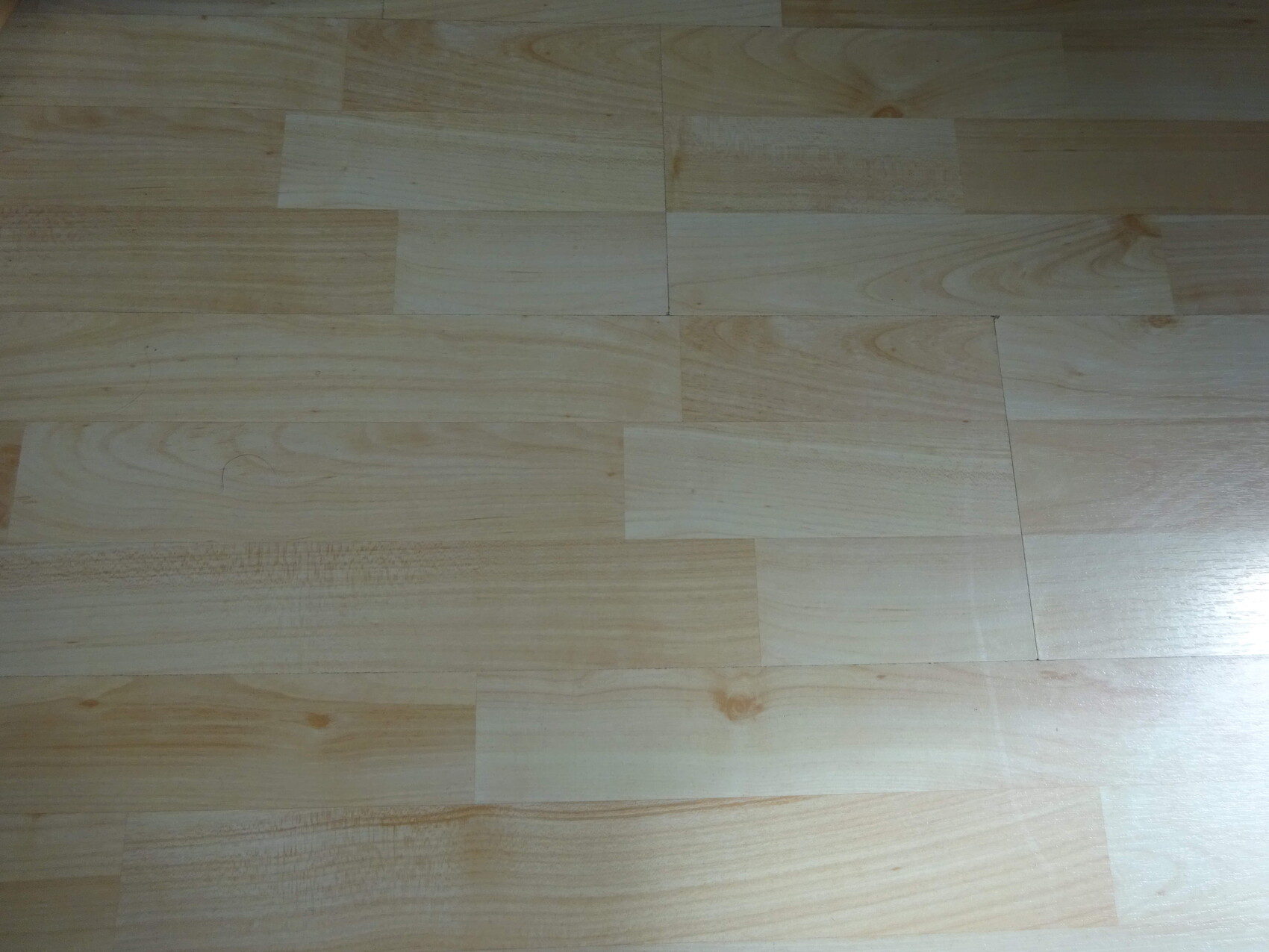 Heller Holzboden mit langen Brettern aus Laminat oder Parkett, ruhige Holzoptik.