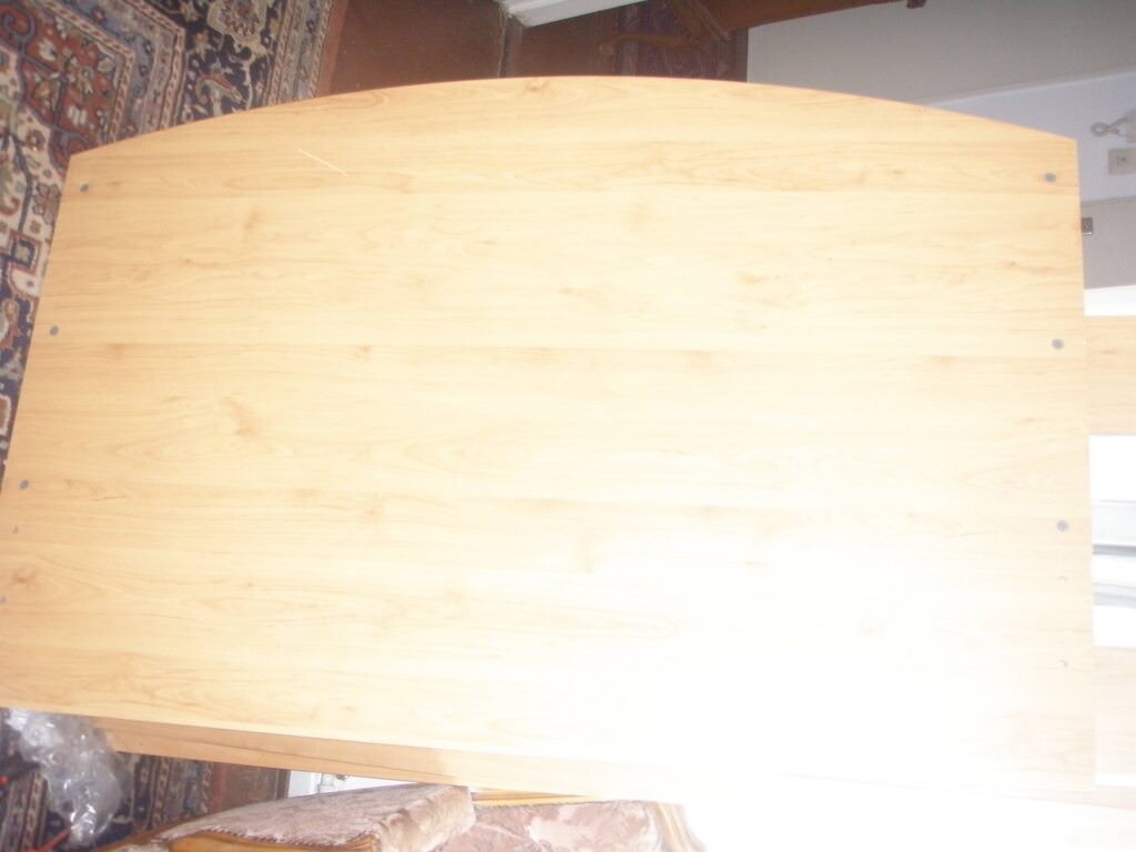 Heller Holztisch aus Holzplatte im Wohnzimmer neben Teppich, unbelegt.