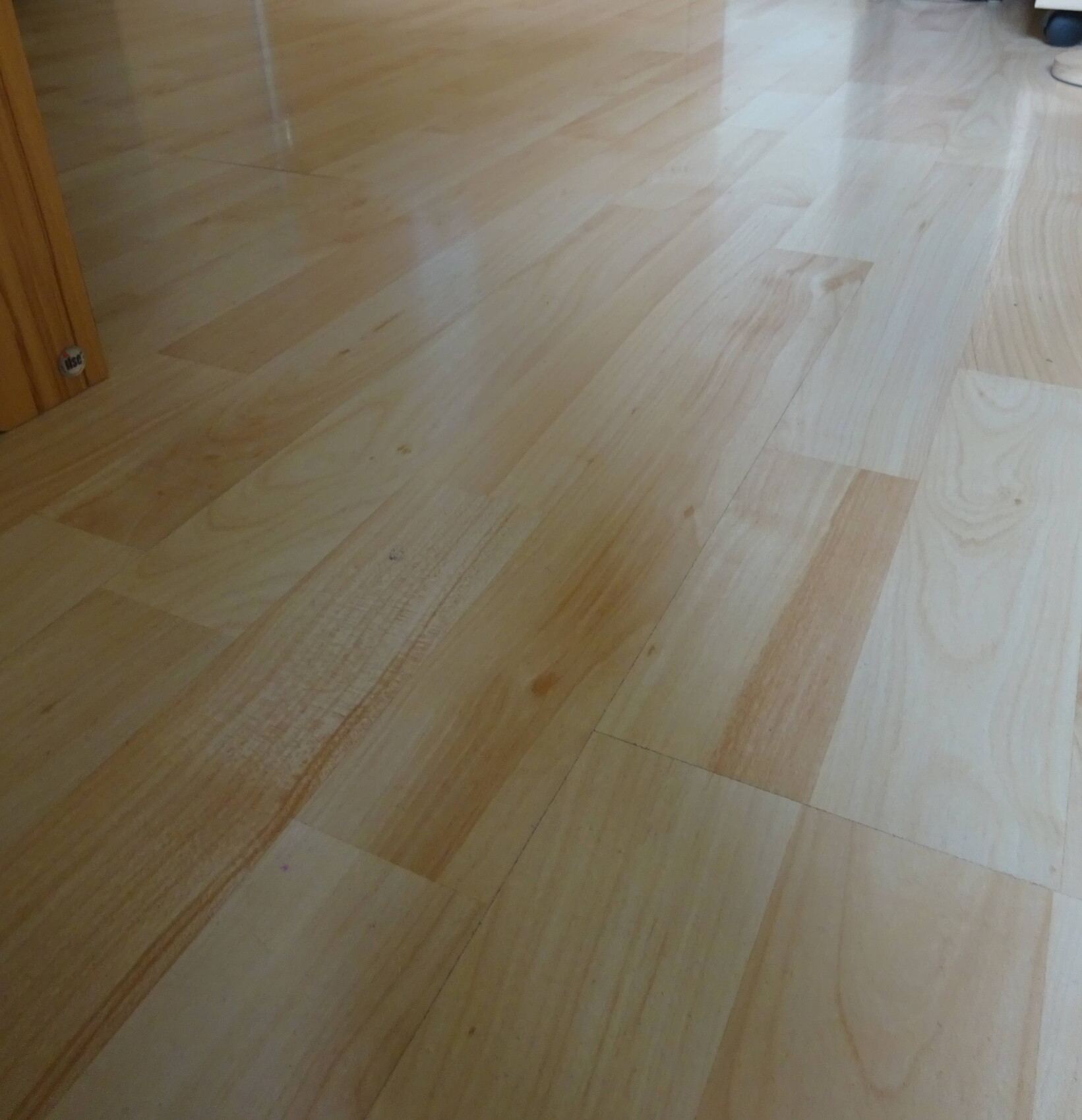 Holzboden mit hellen Planken im Innenraum; Türrahmen links sichtbar.