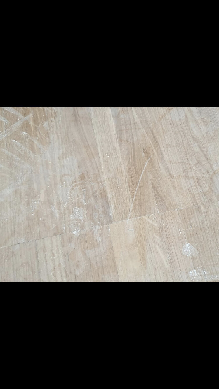 Heller Holzboden mit Staub, weißen Flecken und Kratzern.