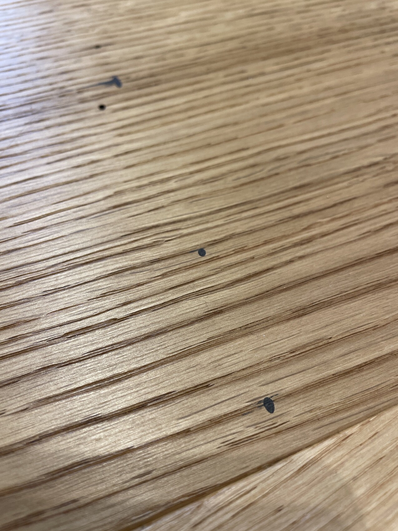 Holzoberfläche mit sichtbarer Maserung und wenigen dunklen Flecken.