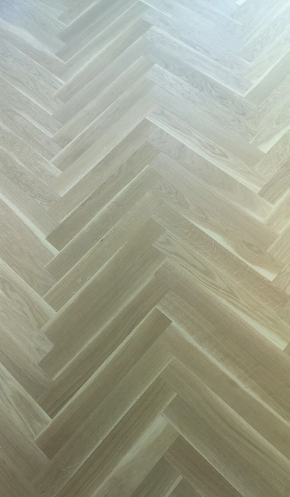 Heller Holzboden im Herringbone-Muster aus schmalen Brettern.