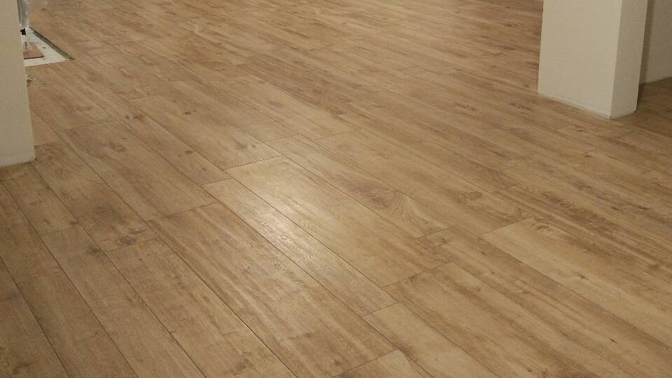Heller Holzboden im Innenraum, Laminat mit sichtbaren Dielen, Wand und Säule rechts.