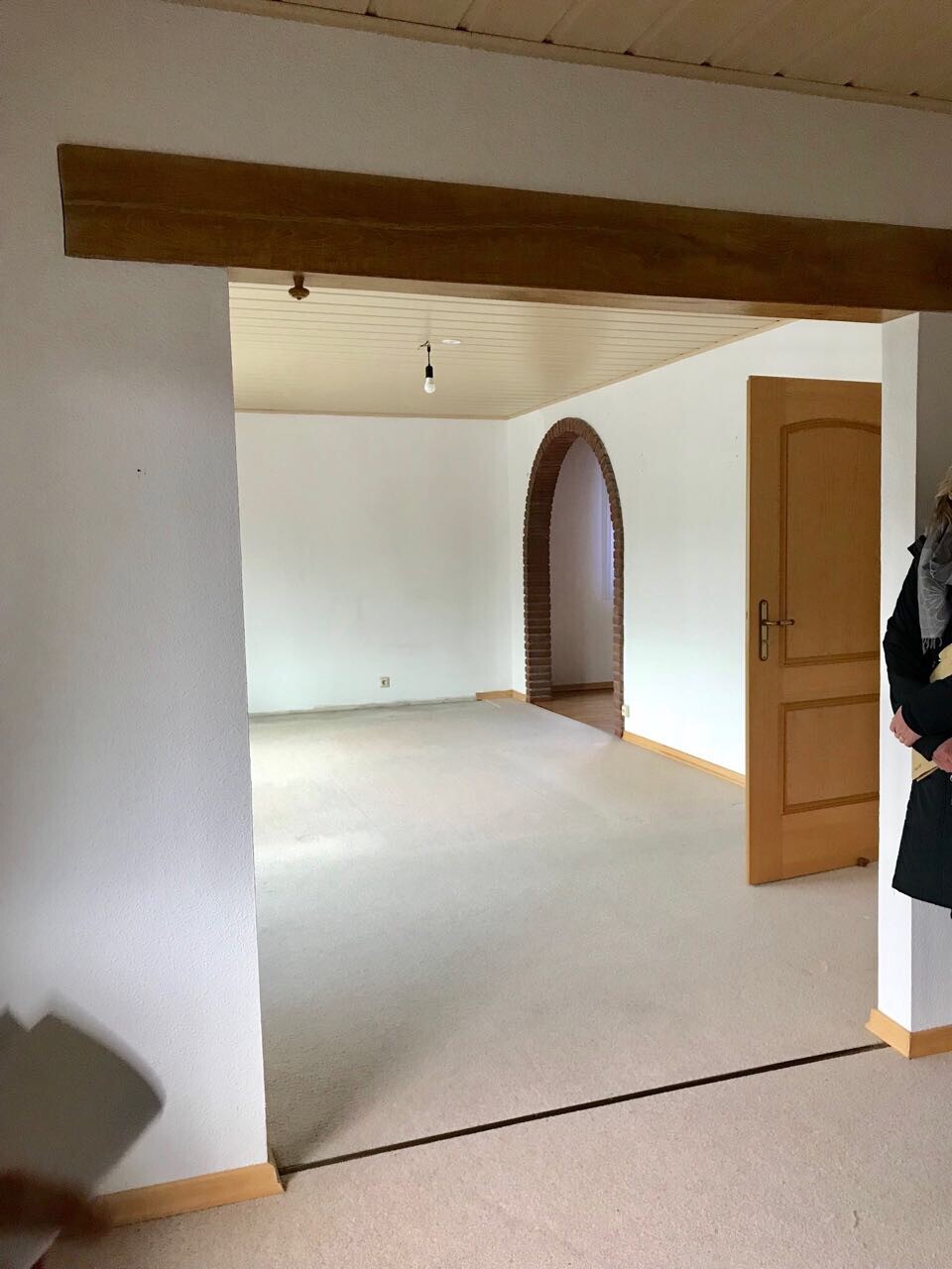 Offener Innenraum mit heller Wand, Holzbalken und gemauertem Bogen-Tor