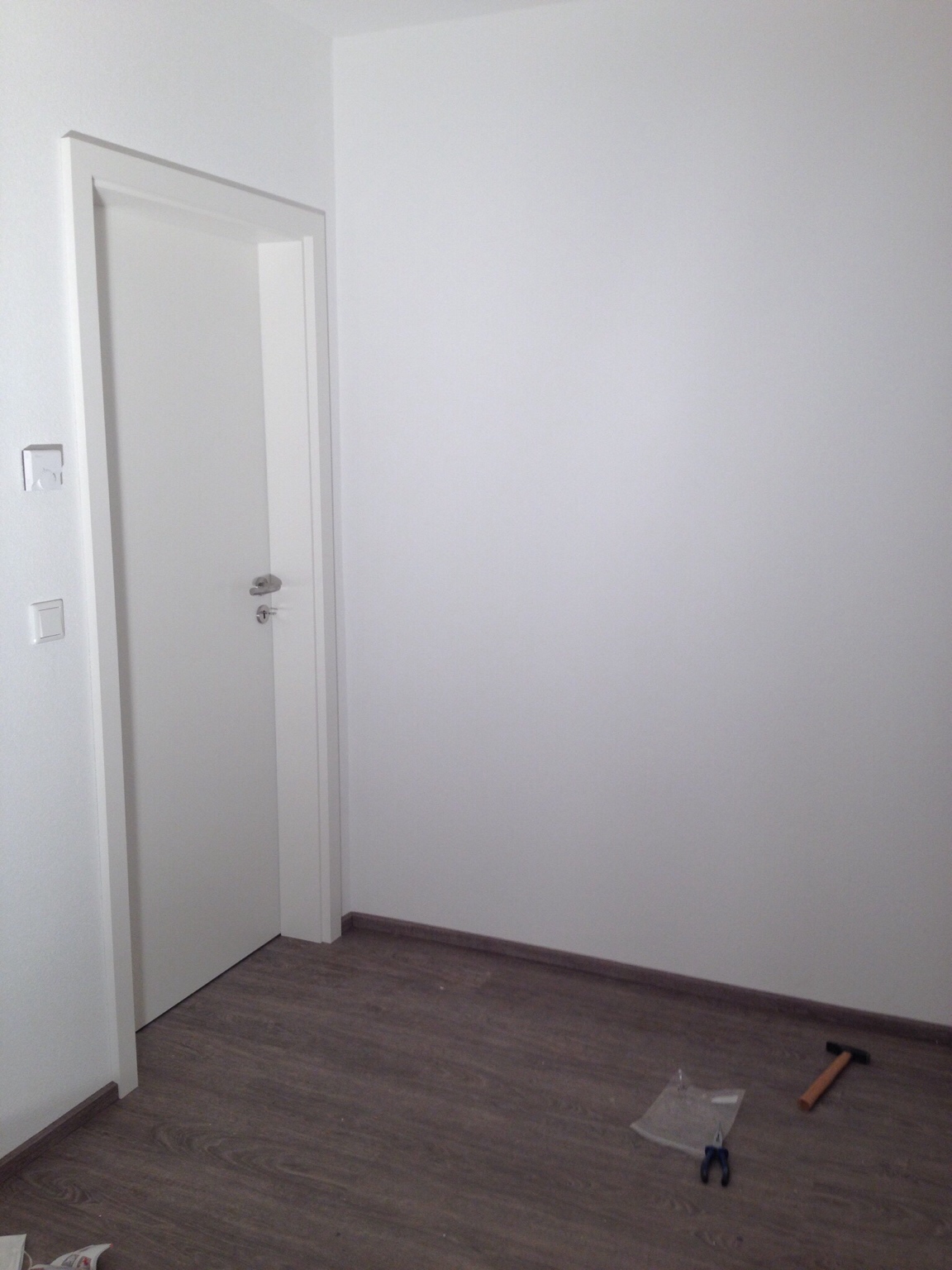 heller-innenraum-mit-weisser-tuer-und-laminatboden-werkzeuge-im-raum.JPG
