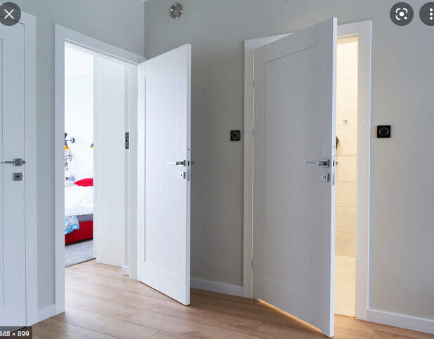 Heller Flur mit drei offenen weißen Türen; Blick ins Schlafzimmer mit Bett und hellem Holzboden.