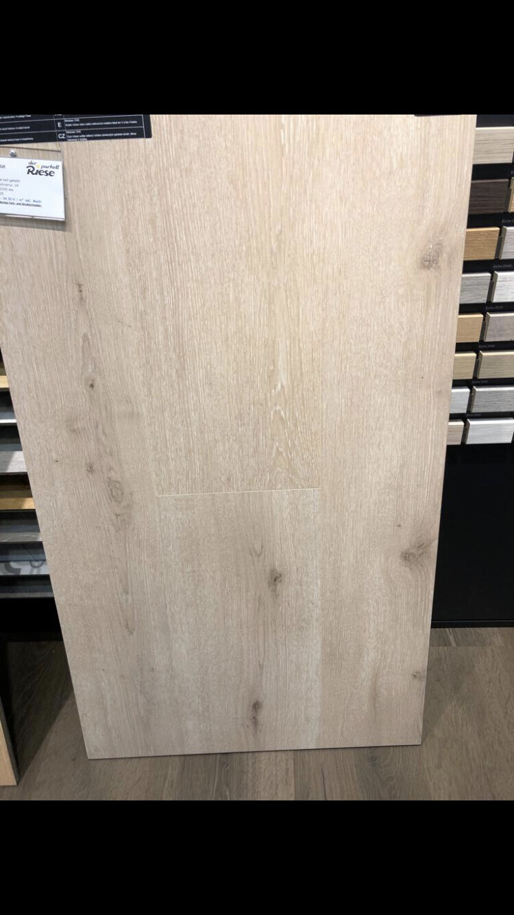 Große helle Holzlaminatplatte steht senkrecht im Möbelgeschäft, rechts Musterplatten sichtbar.