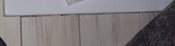 Nahaufnahme eines hellen Laminatbodens mit Sockelleiste und dunklem Randstein