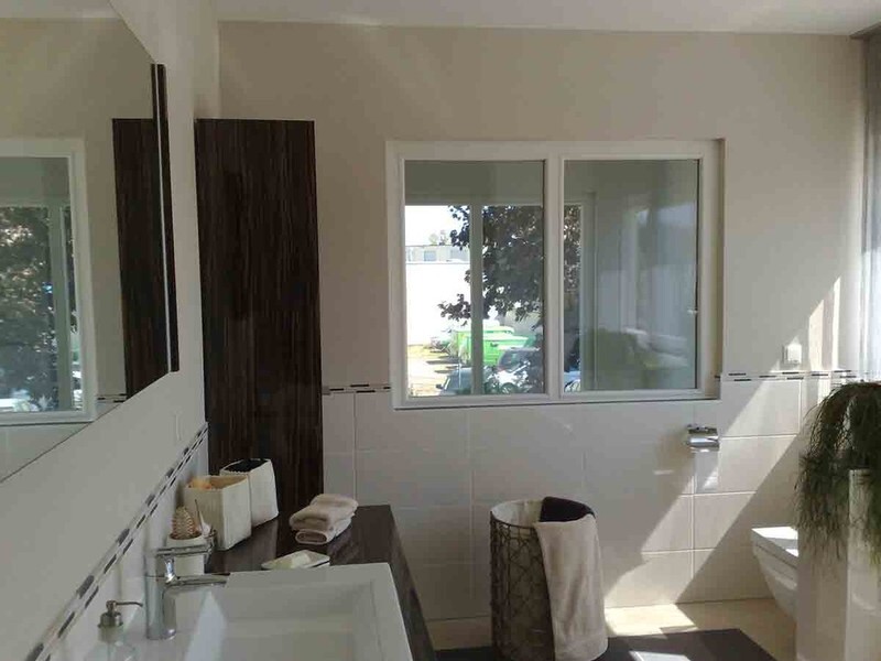 Badezimmer mit Waschbecken, Spiegelschrank, Fenster, Wäschekorb und Pflanze