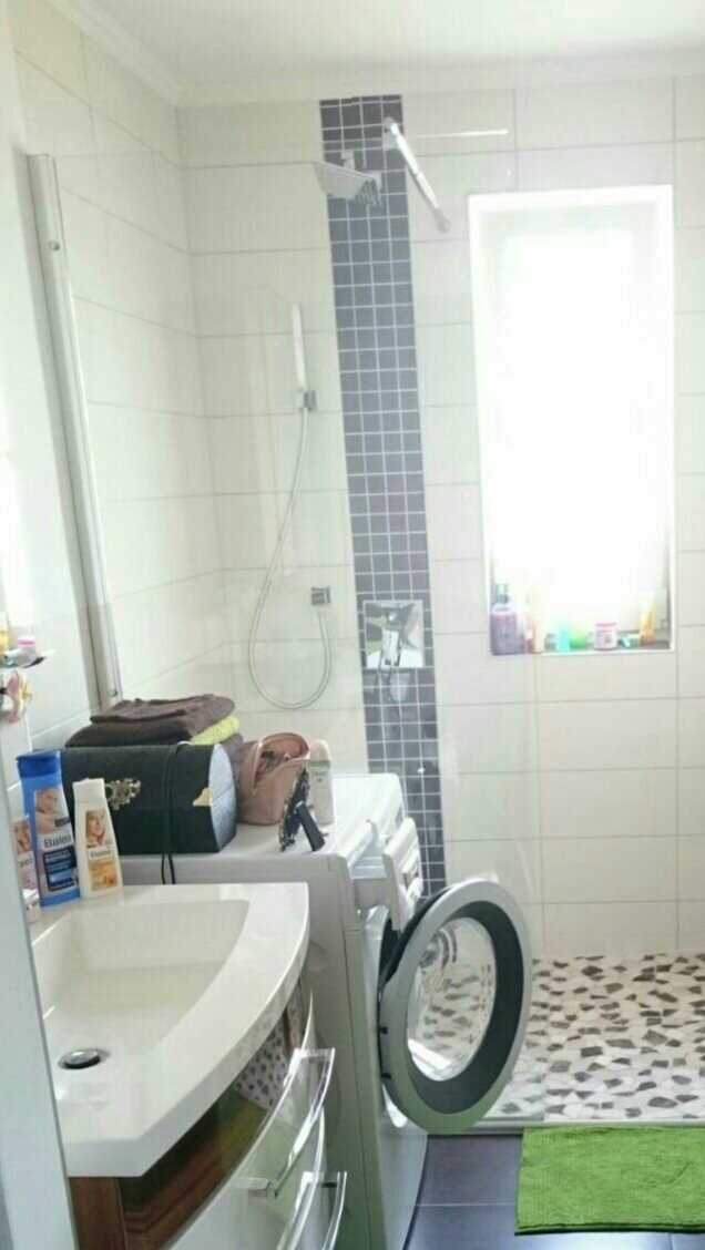 Kleines Badezimmer mit Waschmaschine, Dusche, Waschbecken und Fenster