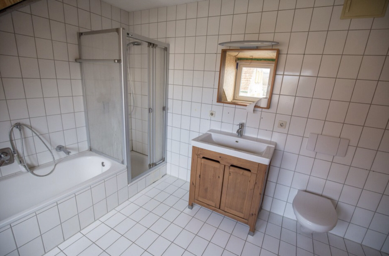 Badezimmer mit Badewanne, Dusche, Waschbecken auf Holzunterschrank und Toilette.