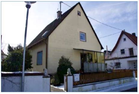 Helles Einfamilienhaus mit spitzem Dach, Terrasse und Holzzaun vor dem Eingangsbereich