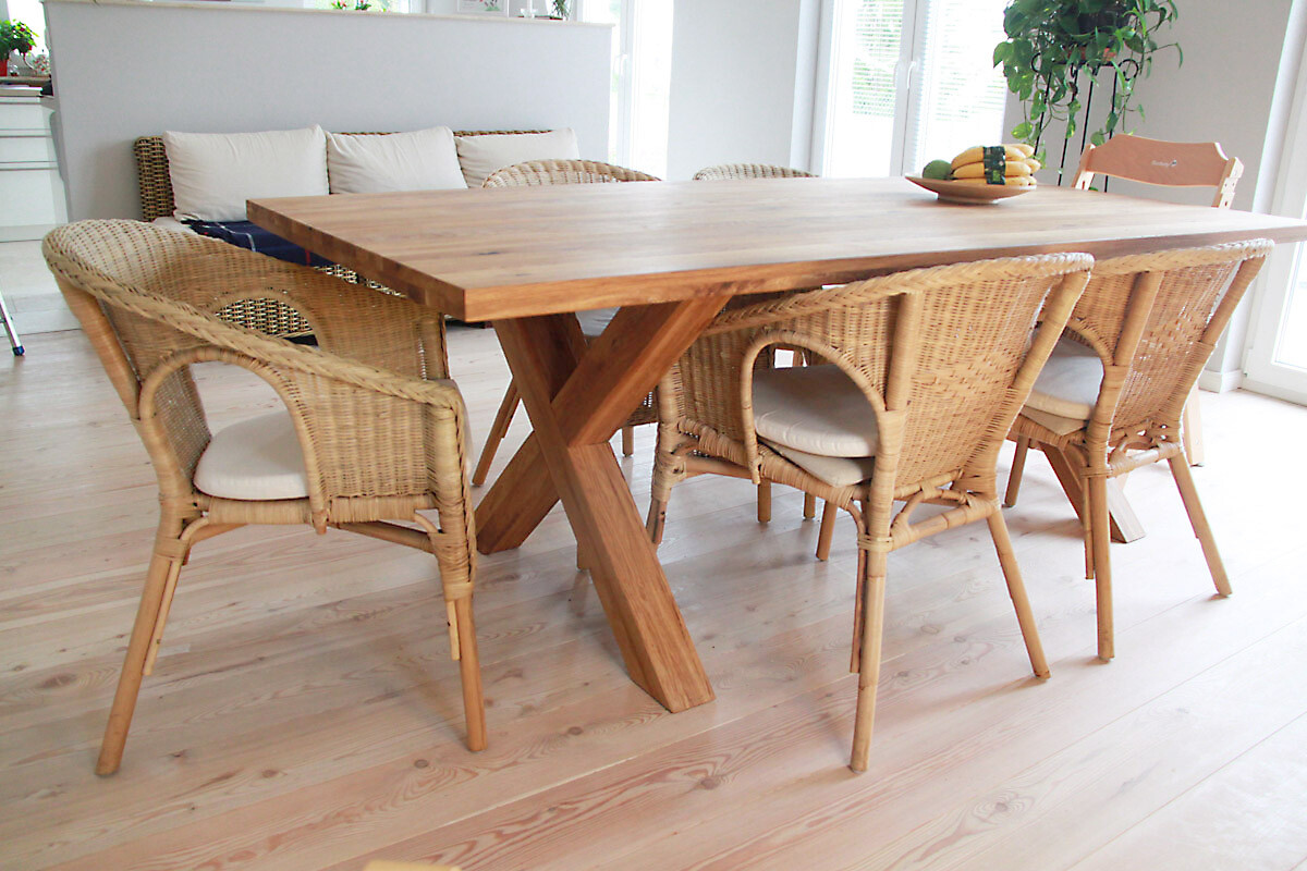 Großer Holztisch mit sechs Rattan-Stühlen in hellem Esszimmer; Obstkorb mit Bananen auf dem Tisch