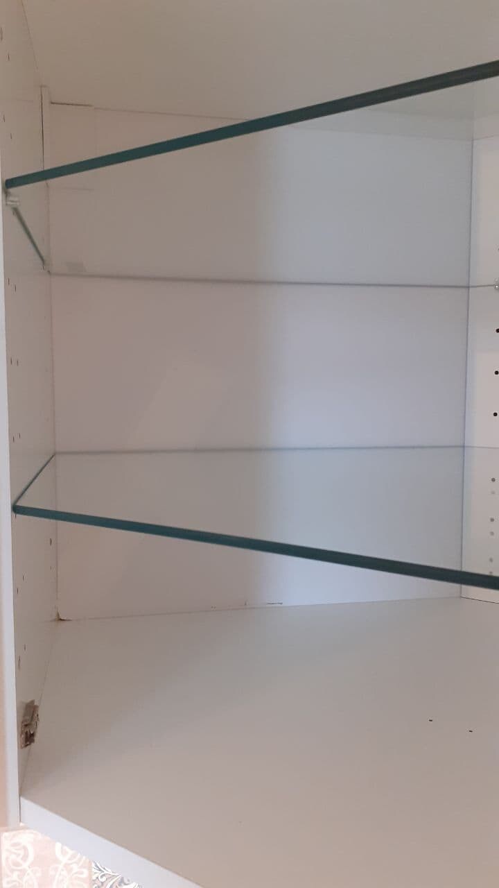 Offener weißer Innenraum eines Schranks mit zwei Glasregalen.