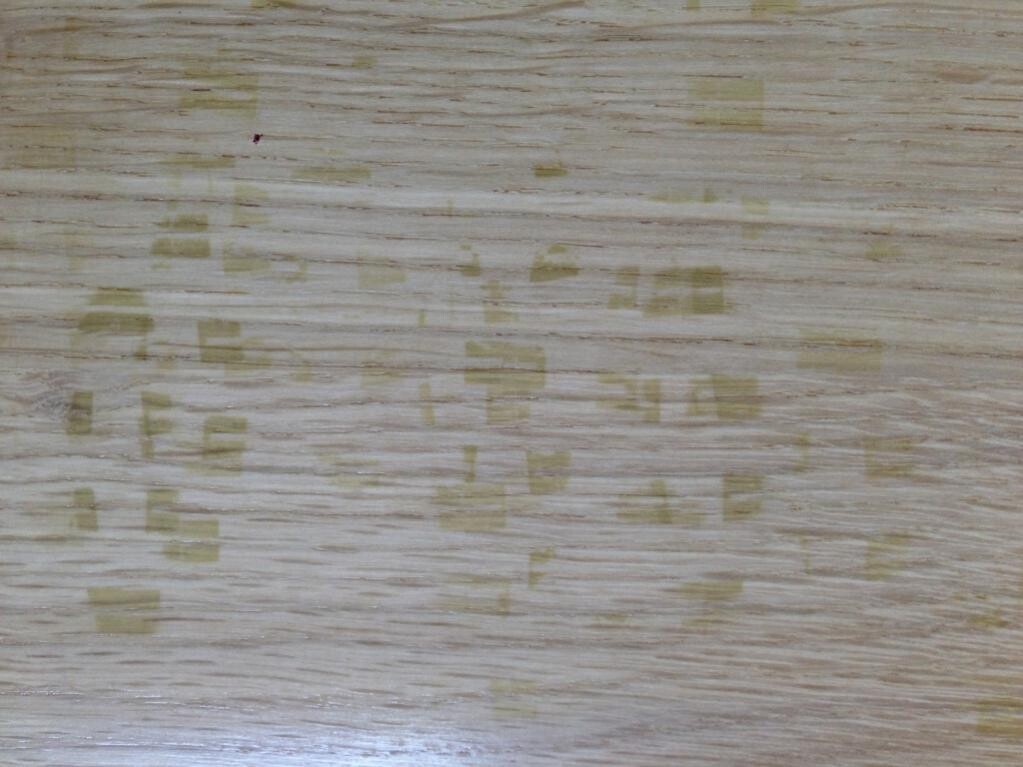 Holzoberfläche mit gelben Klebebandstreifen in unregelmäßigen Mustern