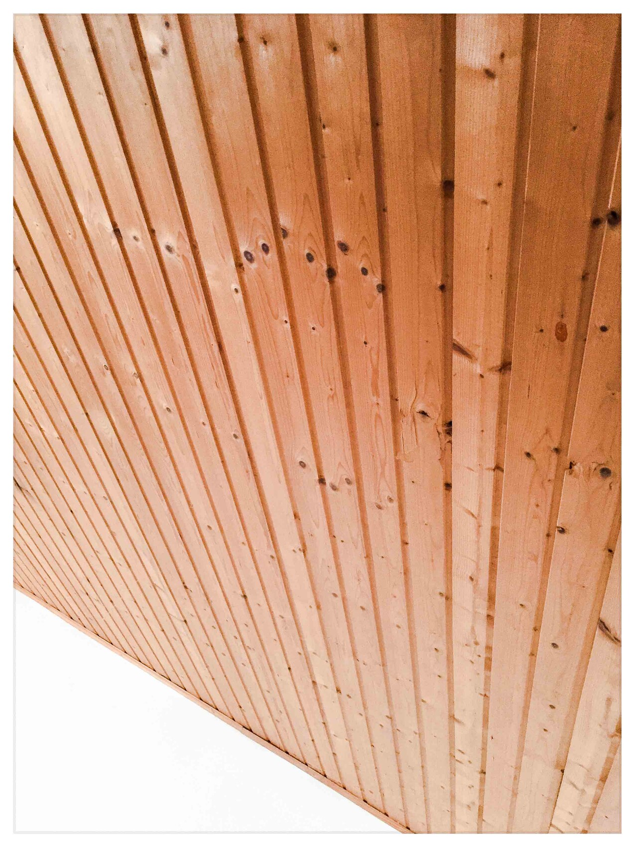 Decke mit parallel verlaufenden, naturbelassenen Holzdielen in Holzoptik.
