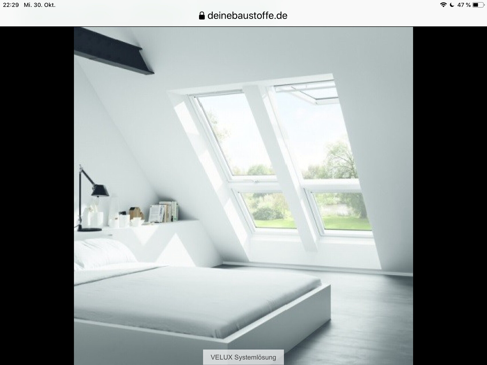 Weißes, minimalistisches Schlafzimmer mit Dachfenstern, Bett, Lampe und Blick ins Grüne.
