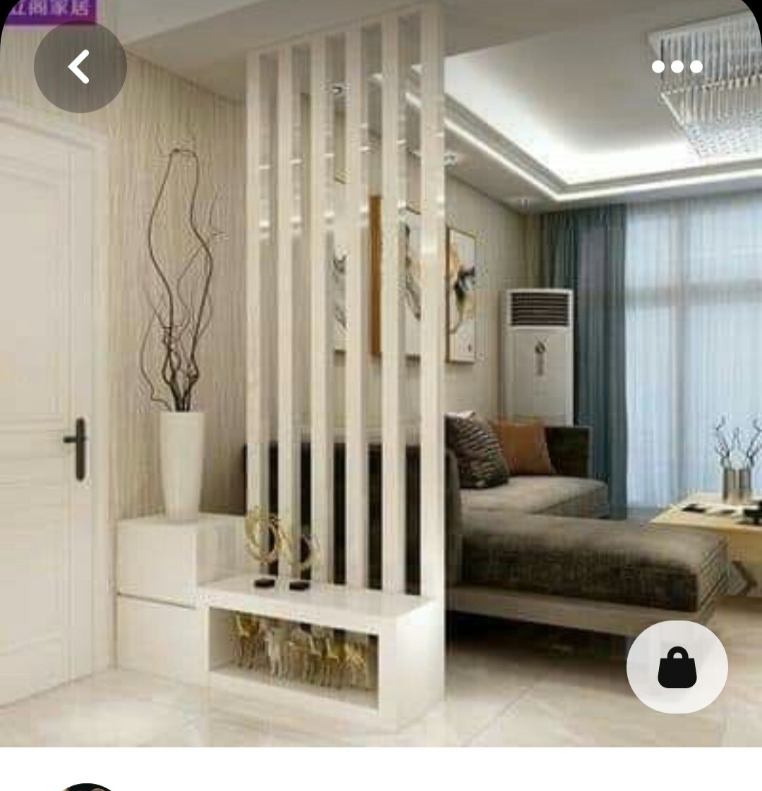 Helles Wohnzimmer mit weißen vertikalen Raumteiler-Stäben, Sofa, Pflanze und Fensterfront.