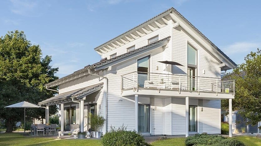 Helles weißes zweistöckiges Haus mit Balkon, Terrasse und Garten.