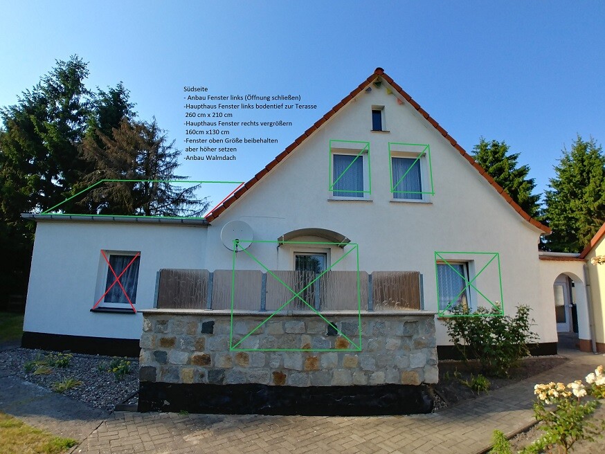 Weißes Einfamilienhaus mit rotem Ziegeldach, Steinmauer davor, Gartenweg und Bäume.