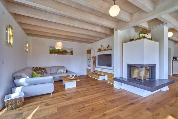 Helles Wohnzimmer mit Kamin, Holzfußboden, Sofa, Couchtisch und TV-Bereich.