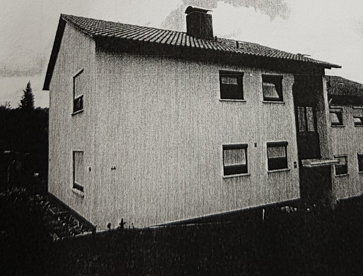 Zweistöckiges, weißes Wohnhaus mit Satteldach, Kamin und mehreren Fenstern.