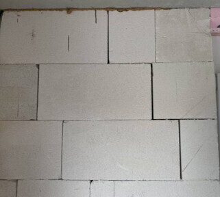 Hellgraue Betonblock-Wand aus rechteckigen Blöcken im Rohbau