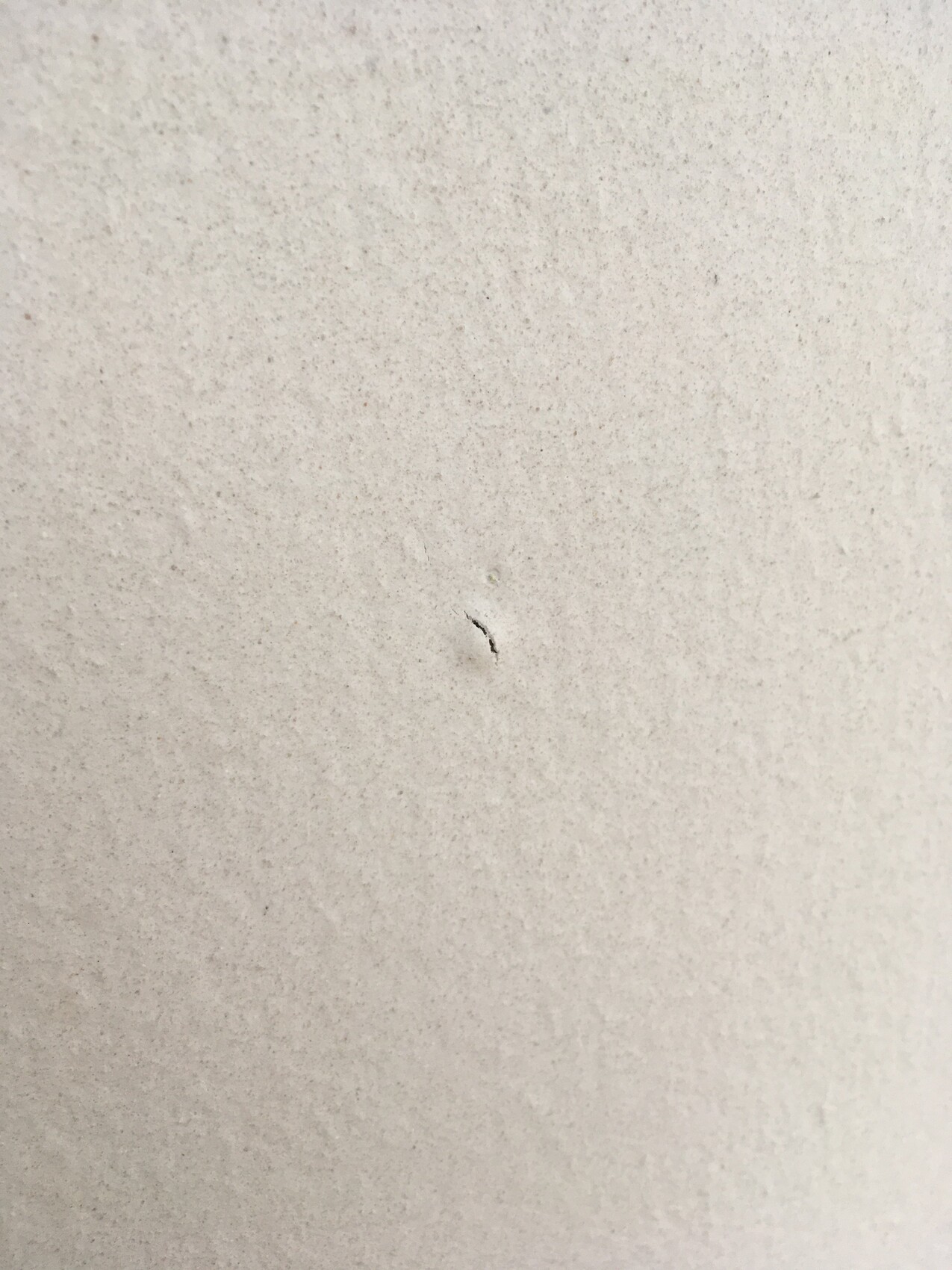 Nahaufnahme einer hellgrauen Betonoberfläche mit kleinem Riss.