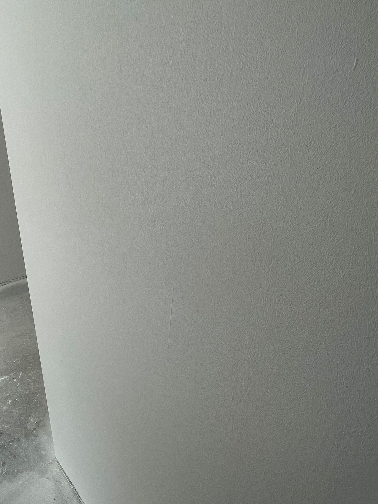 Graue, strukturierte Innenwand mit Ecke; Boden sichtbar