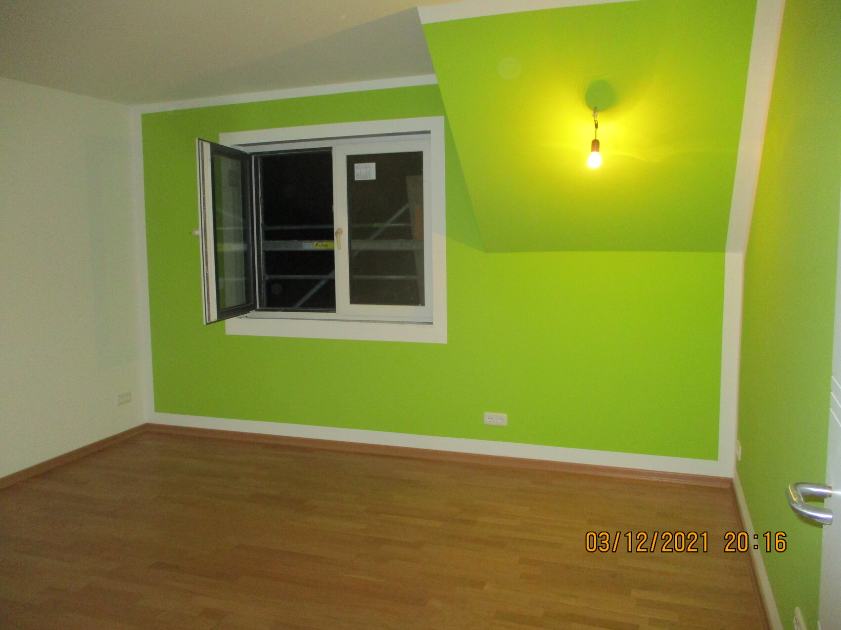 Leeres Zimmer: hellgrüne Wand, offenes Fenster, Holzboden, hängende Glühbirne