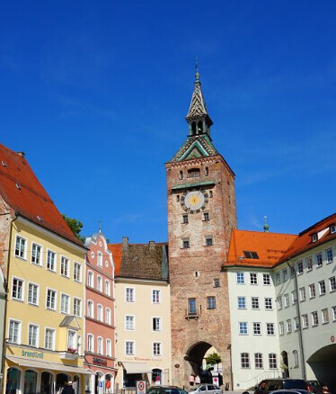 Historischer Stadtplatz mit bunten Häusern und hohem Turm im Zentrum