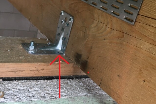 Nahaufnahme eines Holzbalkens mit Metallwinkel-Befestigung im Bau