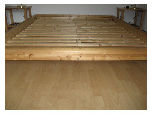 Niedriges Holzbettgestell mit Lattenrost auf hellem Holzboden im Schlafzimmer