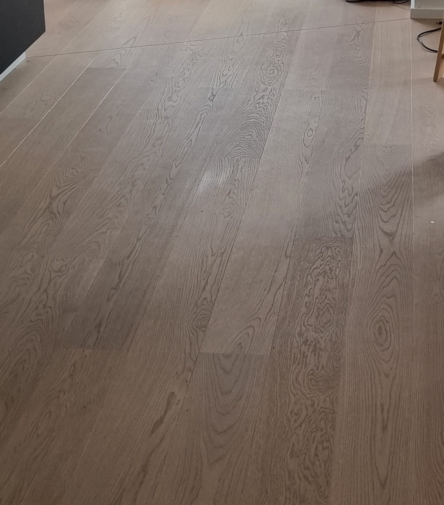 Holzboden mit sichtbarer Maserung, lange parallel verlaufende Dielen in Innenraum.