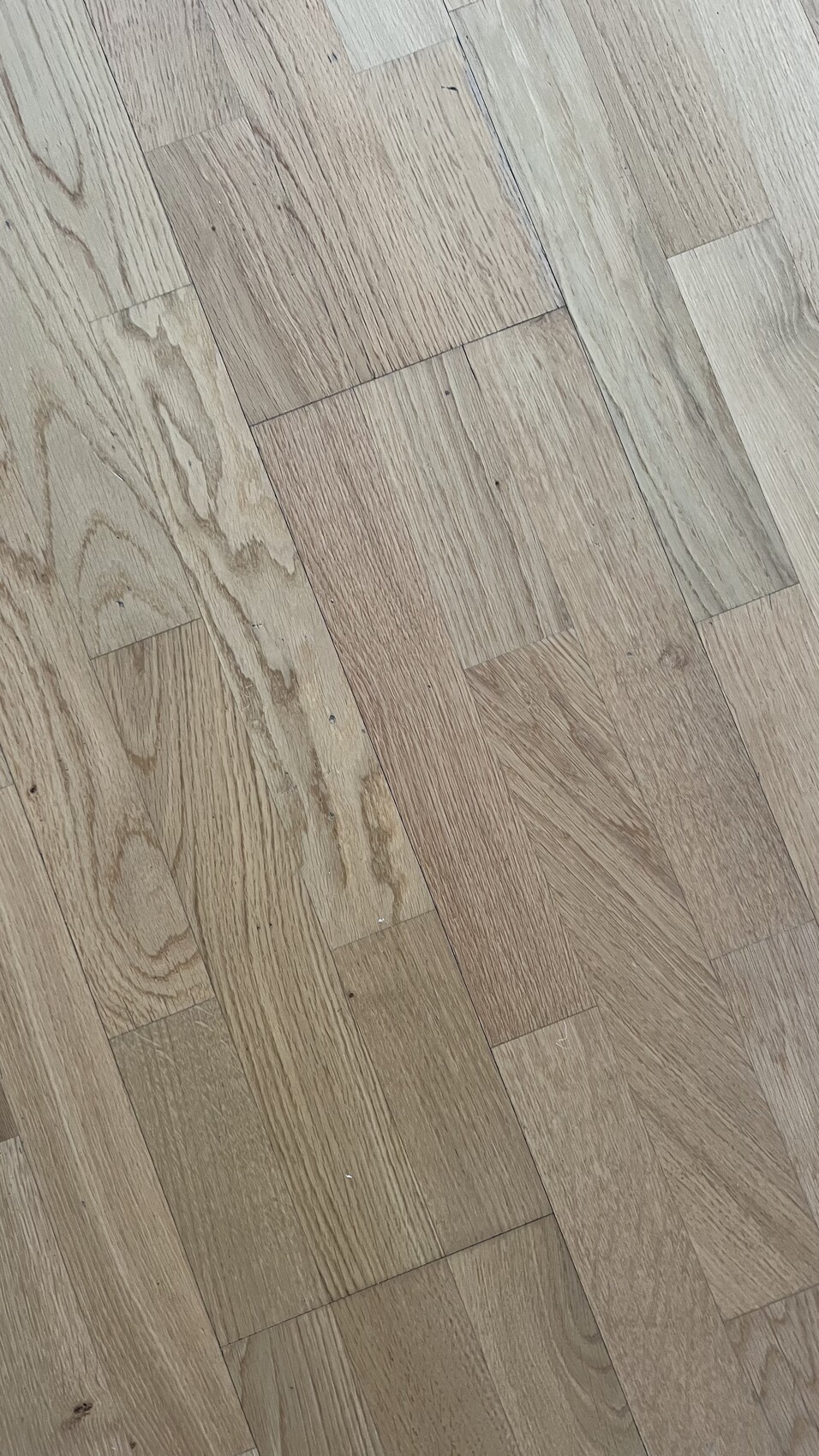 Holzboden mit hellbraunen Parkettbrettern und sichtbarer Maserung in diagonaler Anordnung.
