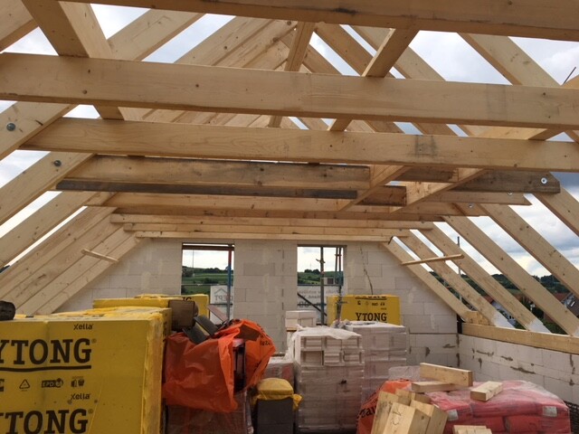 Baustelle mit Holz-Dachstuhl, gelben YTONG-Blocks und Bauholz.