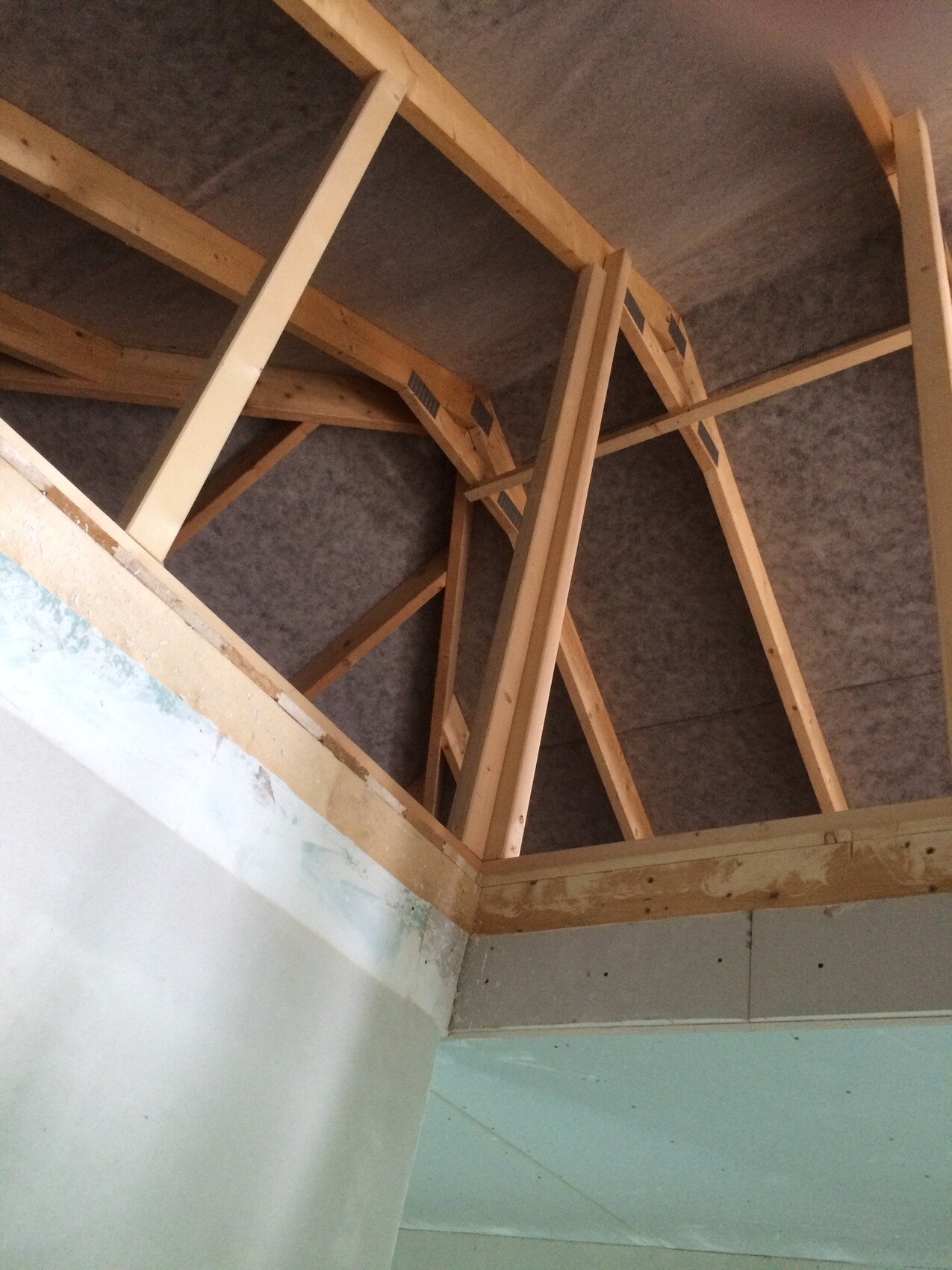 Rohbau: Sichtbare Holz-Dachkonstruktion mit Balken in einem Innenraum.