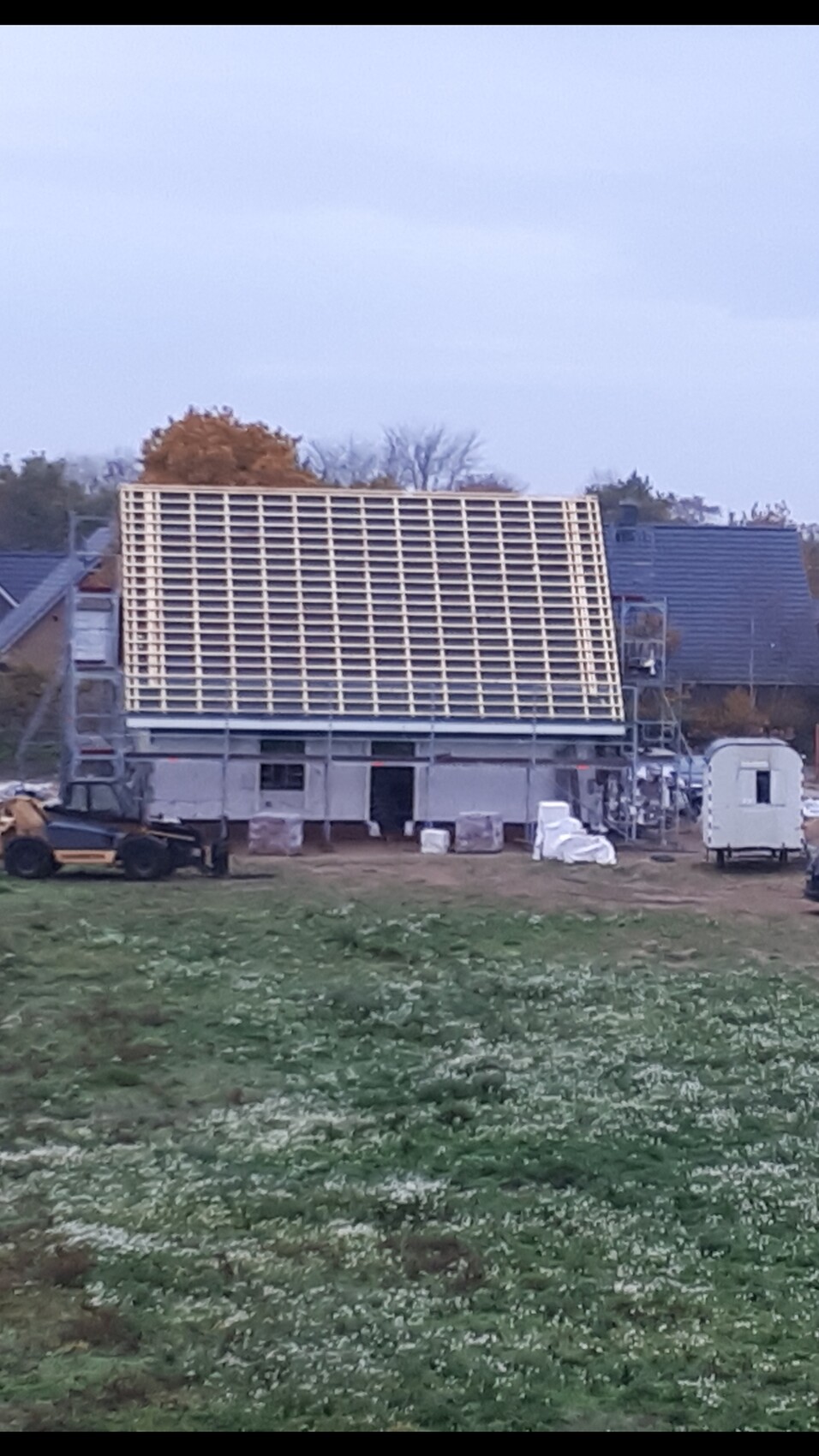 Baustelle: Einfamilienhaus im Rohbau mit Holz-Dachkonstruktion; Baumaschinen und Materialien.