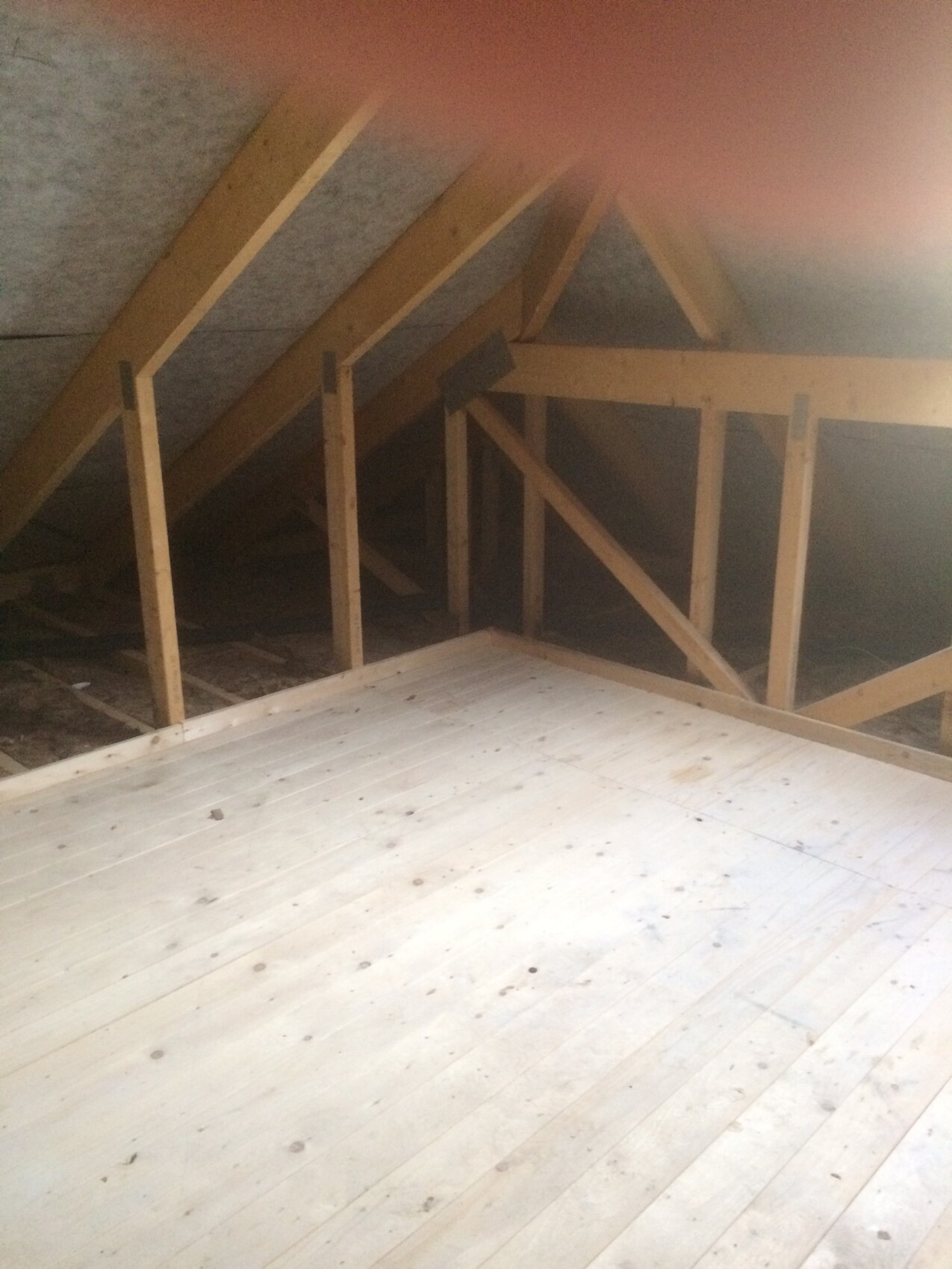 Dachboden mit Holzständerwerk, Sparren und unbehandeltem Holzboden.