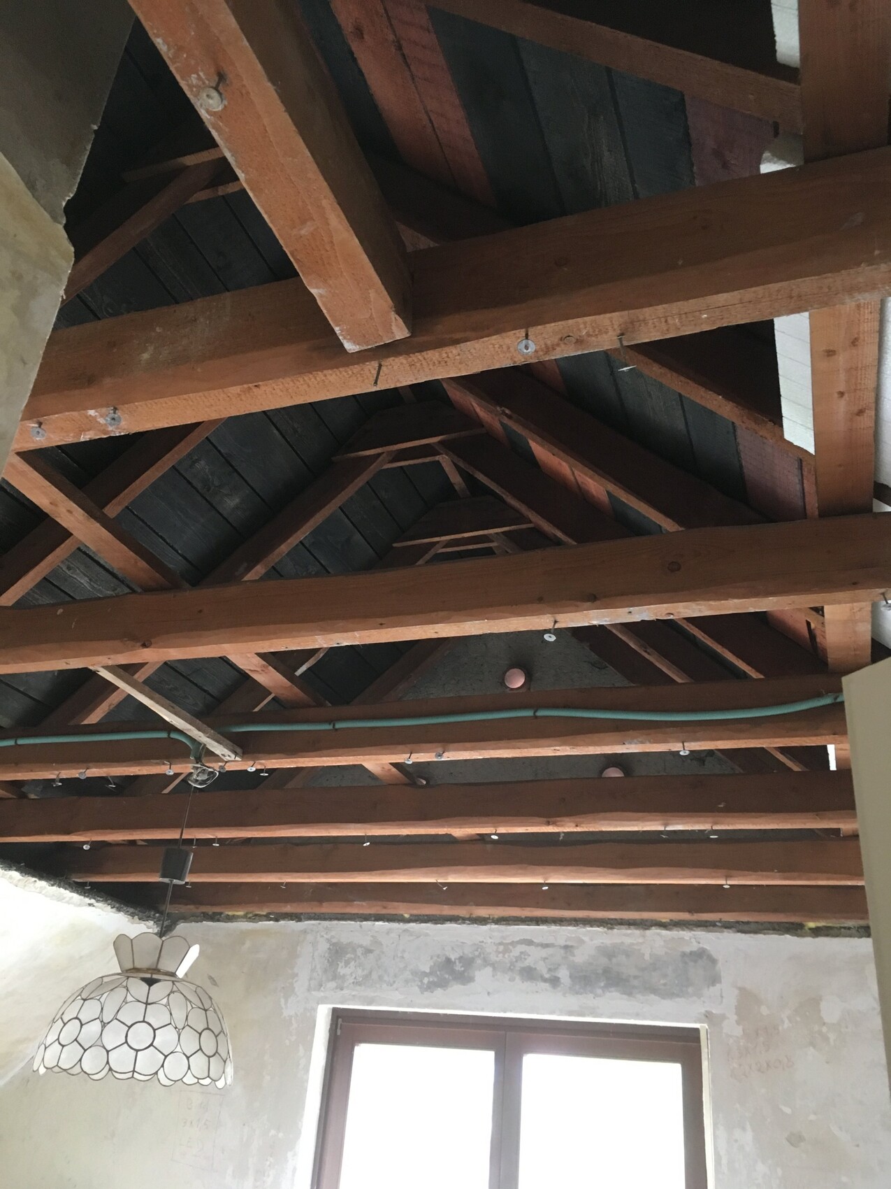 Innenansicht eines Dachstuhls mit Holzbalken im Dachgeschoss und Fenster