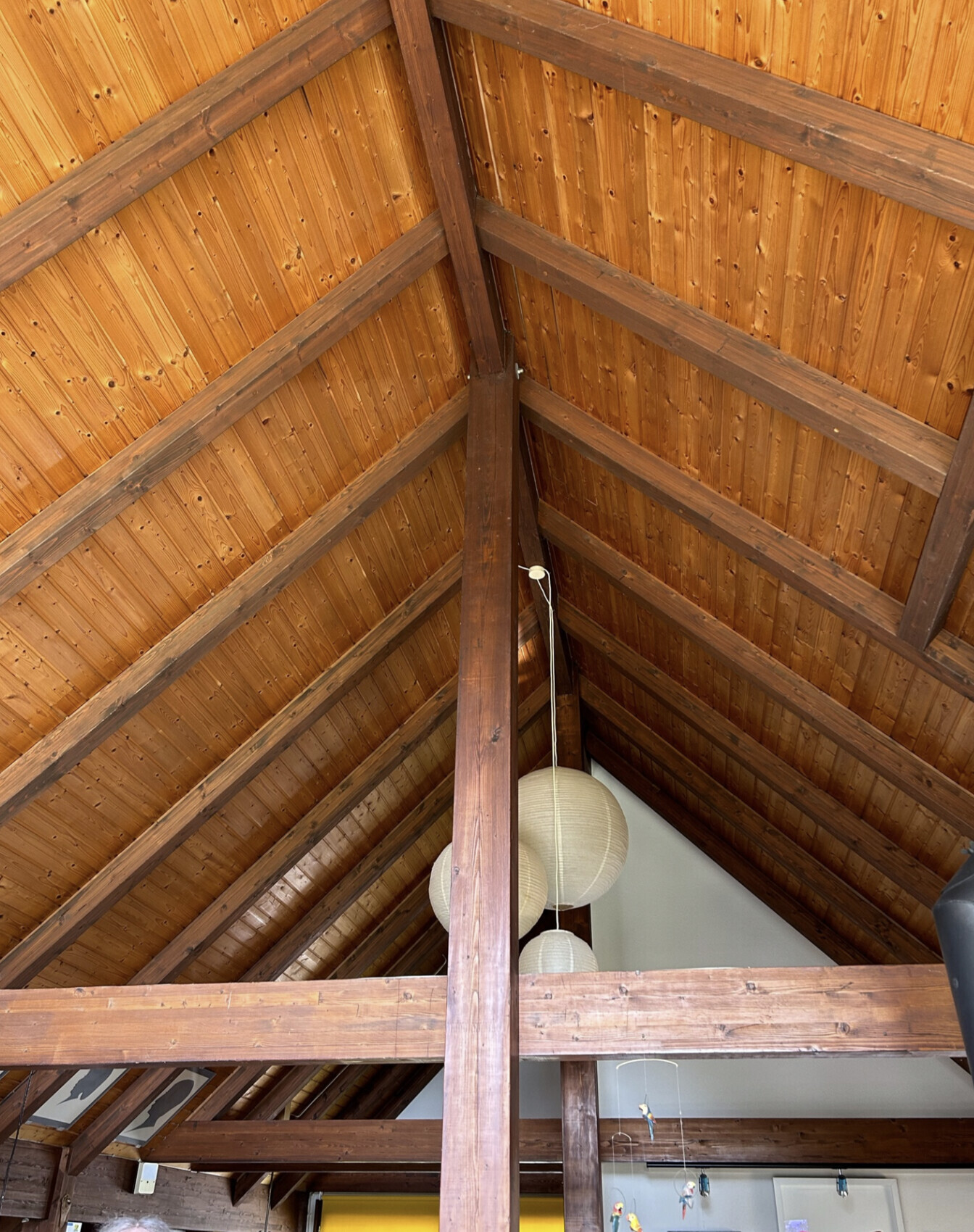 Dachstuhl aus dunklem Holz mit sichtbaren Balken, hängenden weißen Papierlampen.