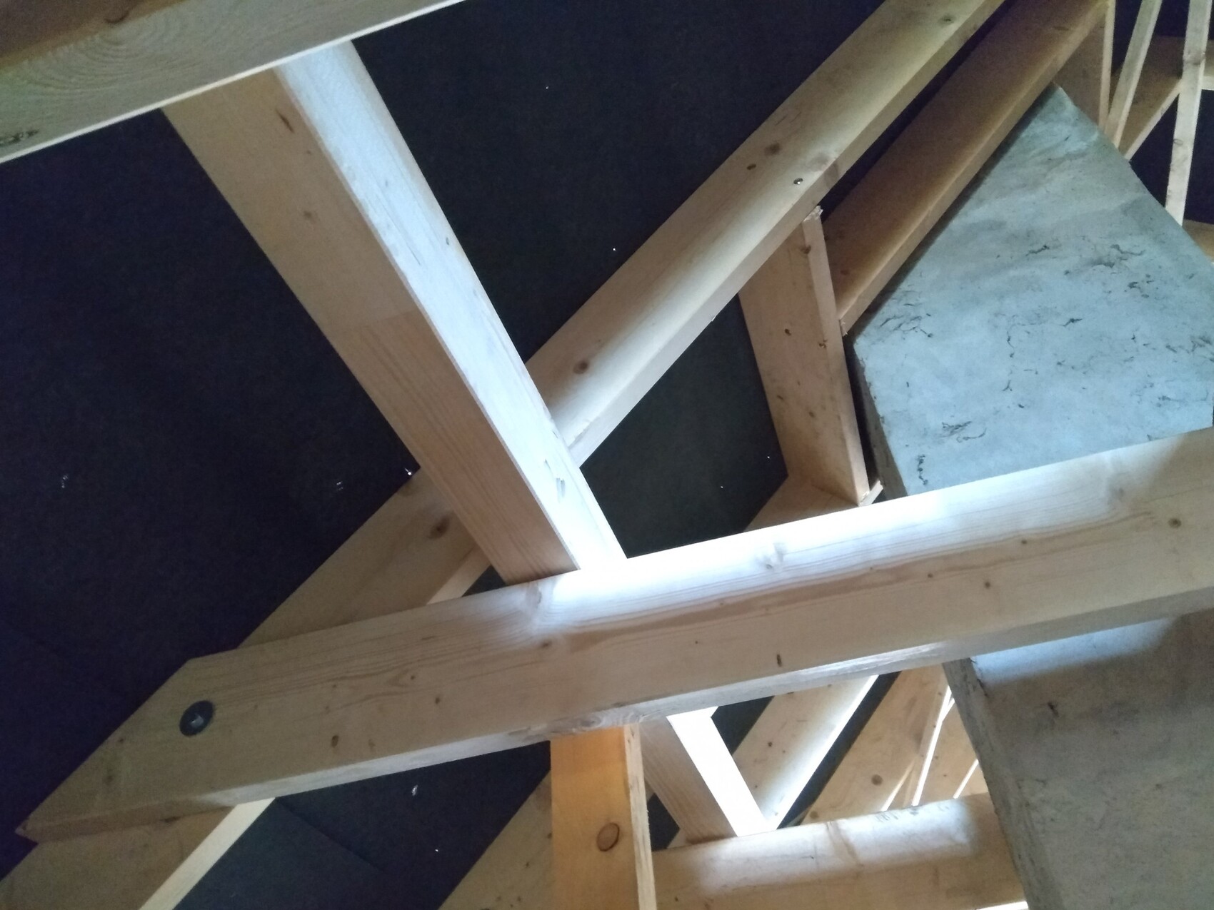 Ansicht eines Dachstuhls mit Holzbalken im Rohbau, sichtbare Dachkonstruktion.