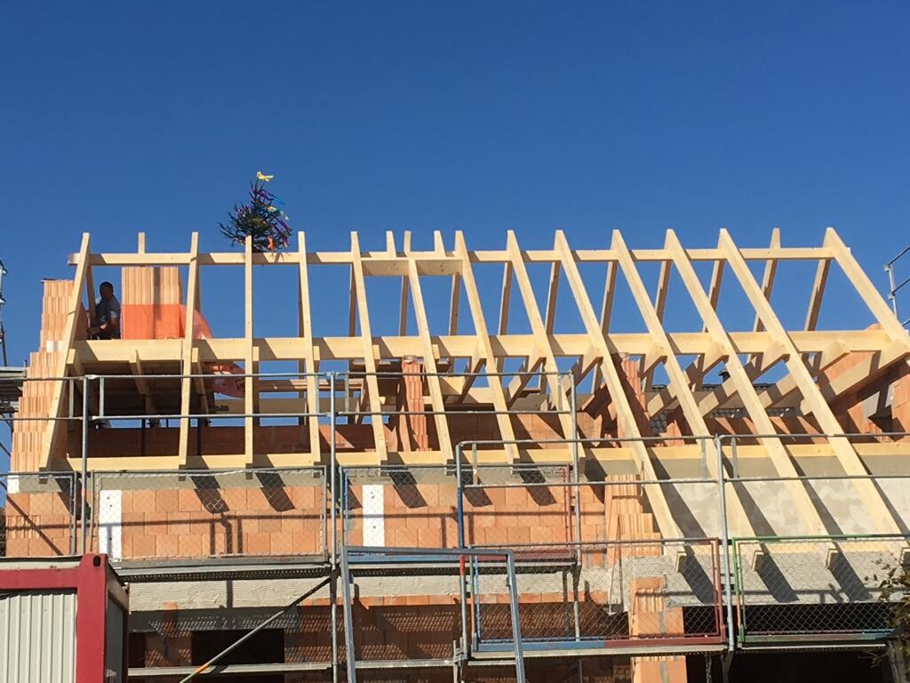 Baustelle mit Holzdachkonstruktion und Gerüst, Backsteinmauern, blauer Himmel