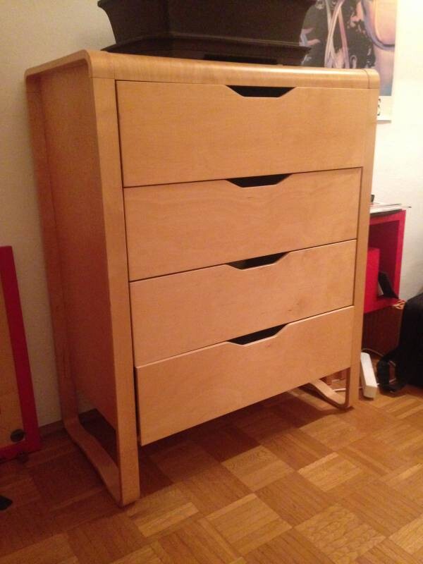 Holz-Kommode mit vier Schubladen steht auf Holzboden in einem Zimmer.
