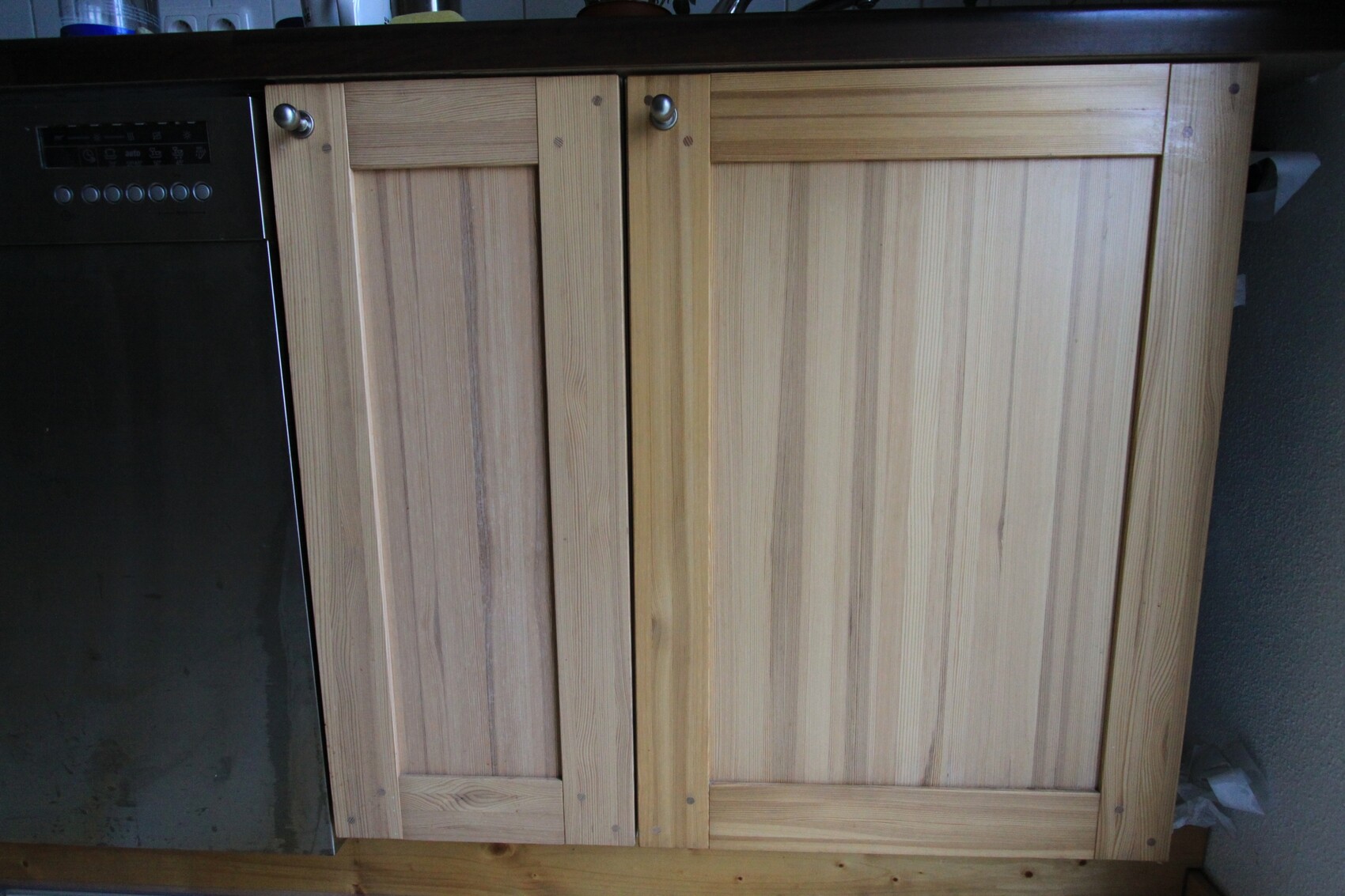 Heller Holzkuechenunterschrank mit Spuelmaschine links in der Kuche