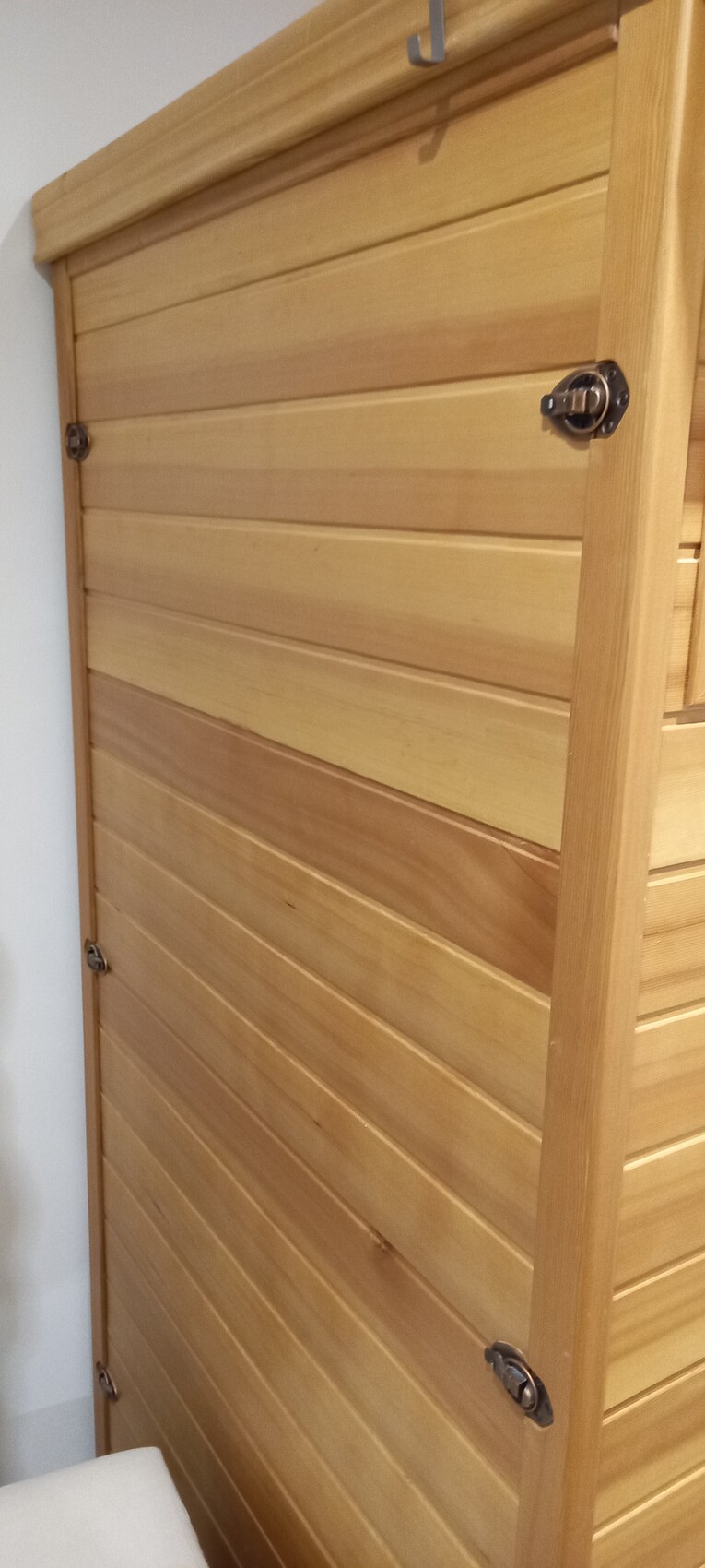 Hölzerne Tür mit horizontalen Holzlatten, Metallverschlüssen und Holzrahmen.