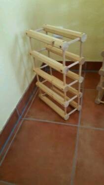 DIY-Holzregal aus Lattenbausteinen steht im Flur neben grüner Wand.