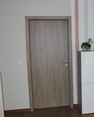 Inneneingangstür aus Holzoptik im Flur mit Holzboden und weißem Sideboard